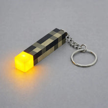 Minecraft torch LED keychain illuminated on a grey background