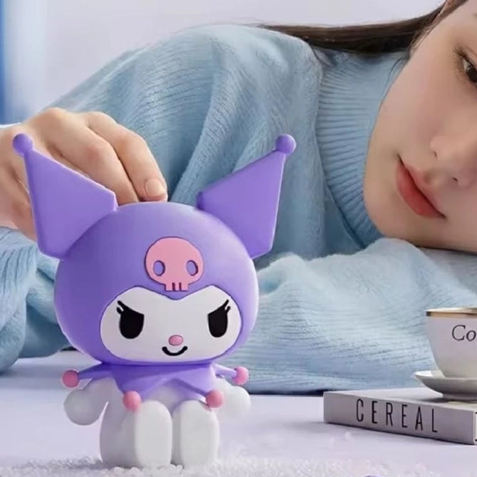 A small Kuromi figurine made of soft purple silicone is shown in a lifestyle setting, with a woman in a light blue sweater touching it. The image includes promotional text for 'Kuromi' and 'Ali Fish' on a light background.